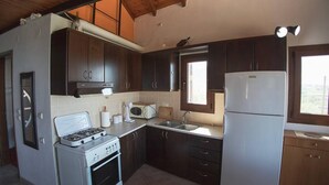 A compact kitchen with dark wooden cabinets, a white stove, a refrigerator, and a window providing natural light.