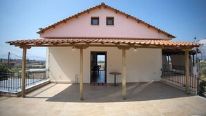 A single-story house with a tiled roof, a covered patio area, and a small table.