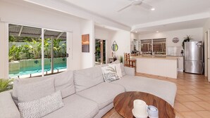 A modern living room with a large grey sofa, a wooden coffee table, and a view of a swimming pool and outdoor area. - Comfortable Family Townhouse, Sunrise Beach (Sunrise Beach)