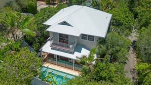 A two-story house with a balcony, surrounded by lush greenery and a swimming pool. - Comfortable Family Townhouse, Sunrise Beach (Sunrise Beach)