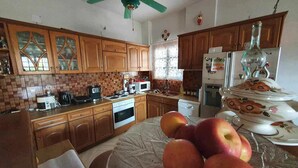 A kitchen with wooden cabinets, a microwave, a stove, and a refrigerator. - Alexia s Residence in Volos (Volos)
