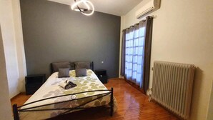 A bedroom with a bed, a radiator, a window with curtains, and an air conditioning unit. - Alexia s Residence in Volos (Volos)