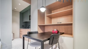 A modern kitchen with a dining table, chairs, and a wooden shelf unit. - Modern Studio Apt w Burj Khalifa View (Dubai)