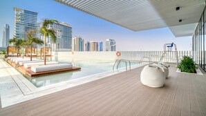 A rooftop pool area with lounge chairs, a water feature, and a view of the city skyline. - Modern Studio Apt w Burj Khalifa View (Dubai)