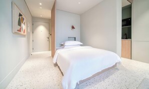 A modern bedroom with a large bed, a wooden wardrobe, and a door leading to another room. - Modern Studio Apt w Burj Khalifa View (Dubai)