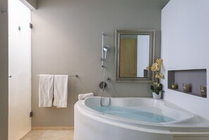 Un baño moderno con una bañera independiente, un espejo grande y una orquídea en maceta.
