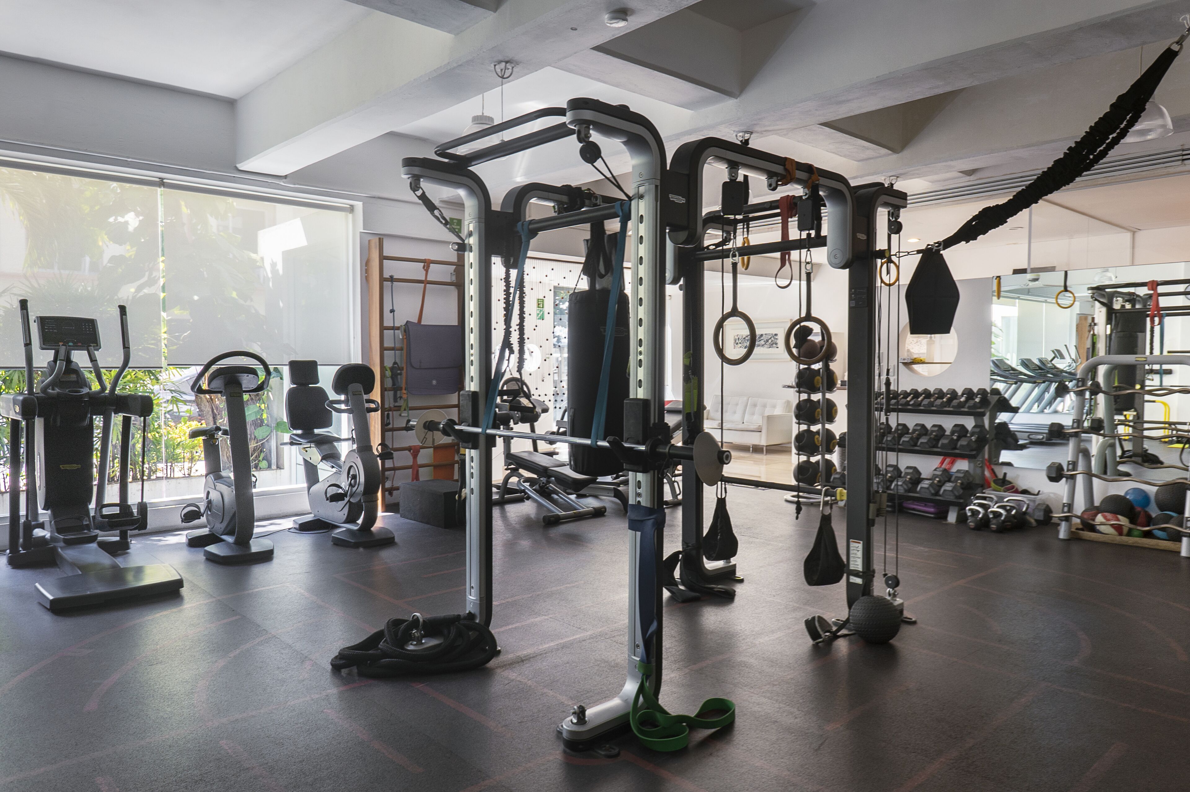 Ein Fitnessstudio mit verschiedenen Trainingsgeräten, darunter Laufbänder, Kraftgeräte und Kurzhanteln.