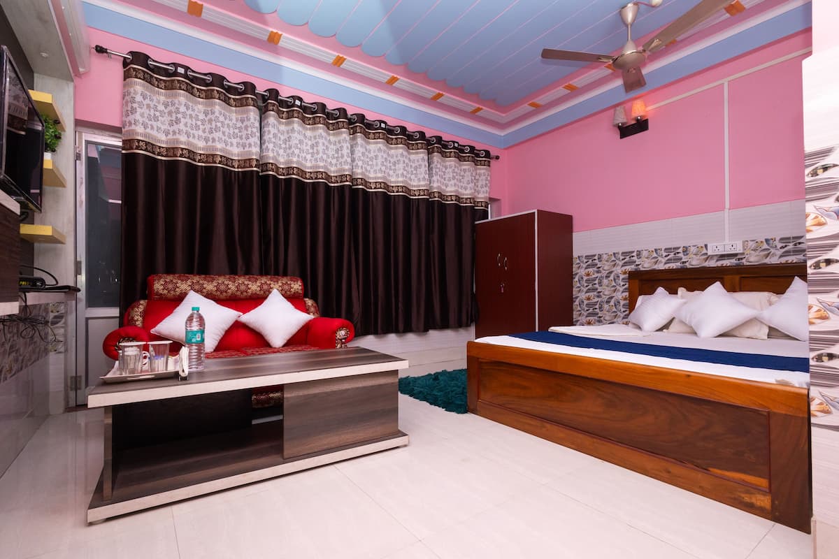 A bedroom with a bed, a sofa, a TV stand, and a wardrobe.