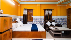 A hotel room with two beds, a wooden wardrobe, a sofa, a coffee table, and patterned curtains. - RAJA HOTEL AND LODGE  (Kharagpur)