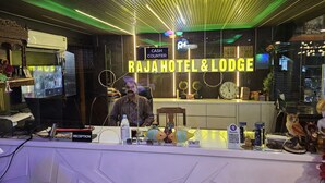 A reception desk at Rajahotel & Lodge with a modern design, a cash counter, and a visible clock. - RAJA HOTEL AND LODGE  (Kharagpur)