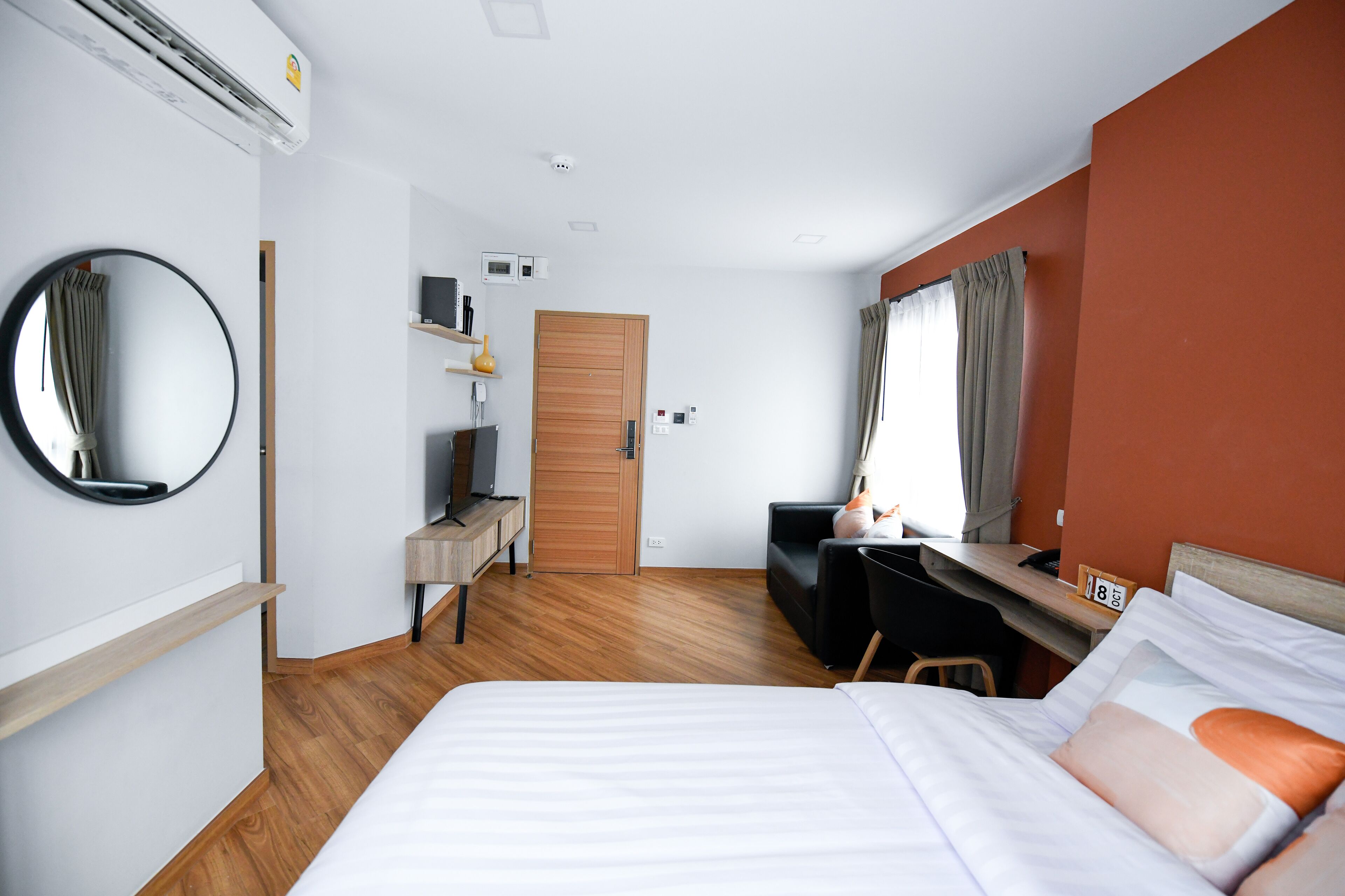 A hotel room with a bed, a desk, a chair, a TV, and a wardrobe.