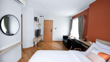 A hotel room with a bed, a desk, a chair, a TV, and a wardrobe.