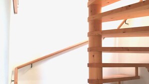 A wooden spiral staircase with a handrail and a landing platform.