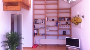 A room with a wooden bookshelf, a radiator, a TV, and a plant.