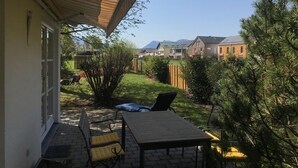 A patio with a table and chairs, a covered area, and a view of houses and mountains in the background.