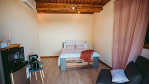 Un dormitorio pequeño con cama, una mesita de centro, un sofá y un refrigerador.