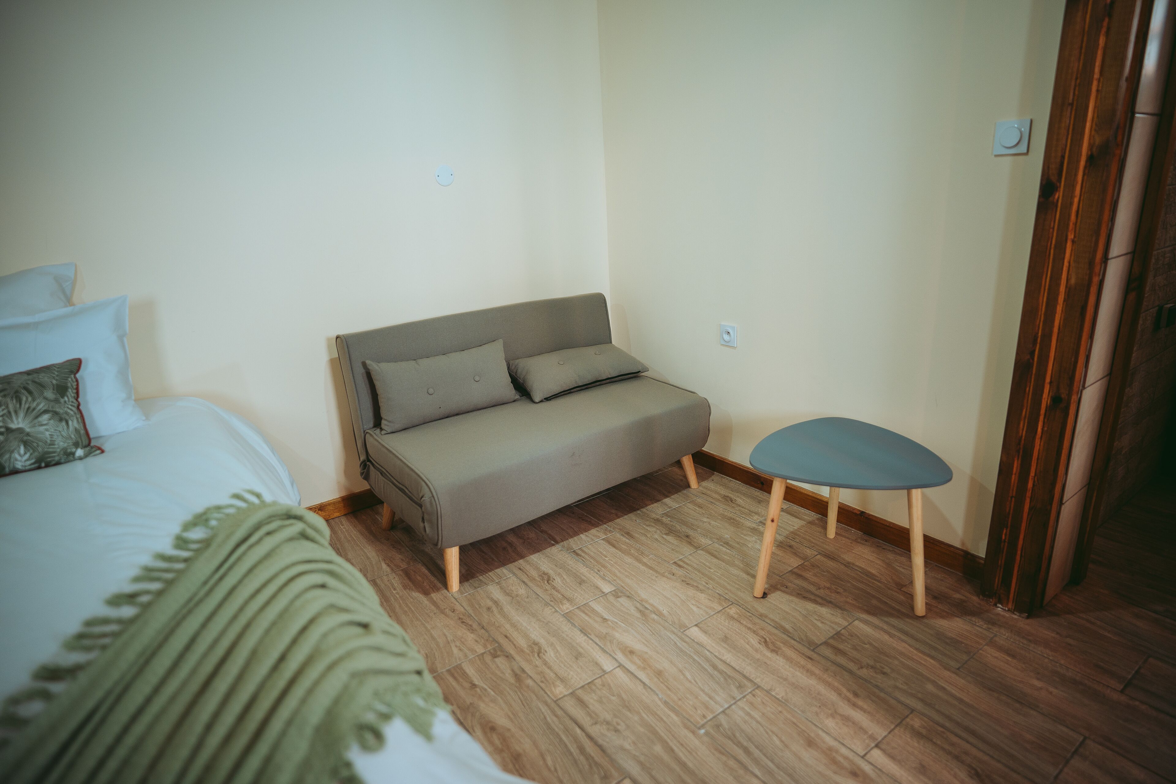 Ein Zimmer mit einem Bett, einem Schlafsofa, einem kleinen Tisch und Holzboden.