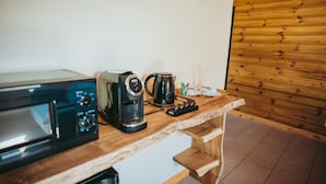 Una kitchenette con microondas, cafetera y hervidor sobre una encimera de madera.
