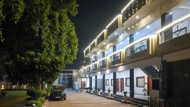 A multi-story hotel with a modern design, featuring balconies and a well-lit entrance. - The Kedar Resort (Mathura)