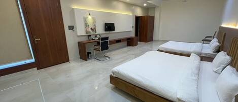 A modern hotel room with two beds, a desk, a chair, and a TV.