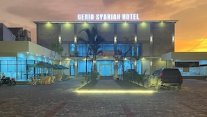 The exterior of Genio Syariah Hotel with a paved entrance and a clear sky in the background. - Genio Syariah Hotel Solo (Surakarta)