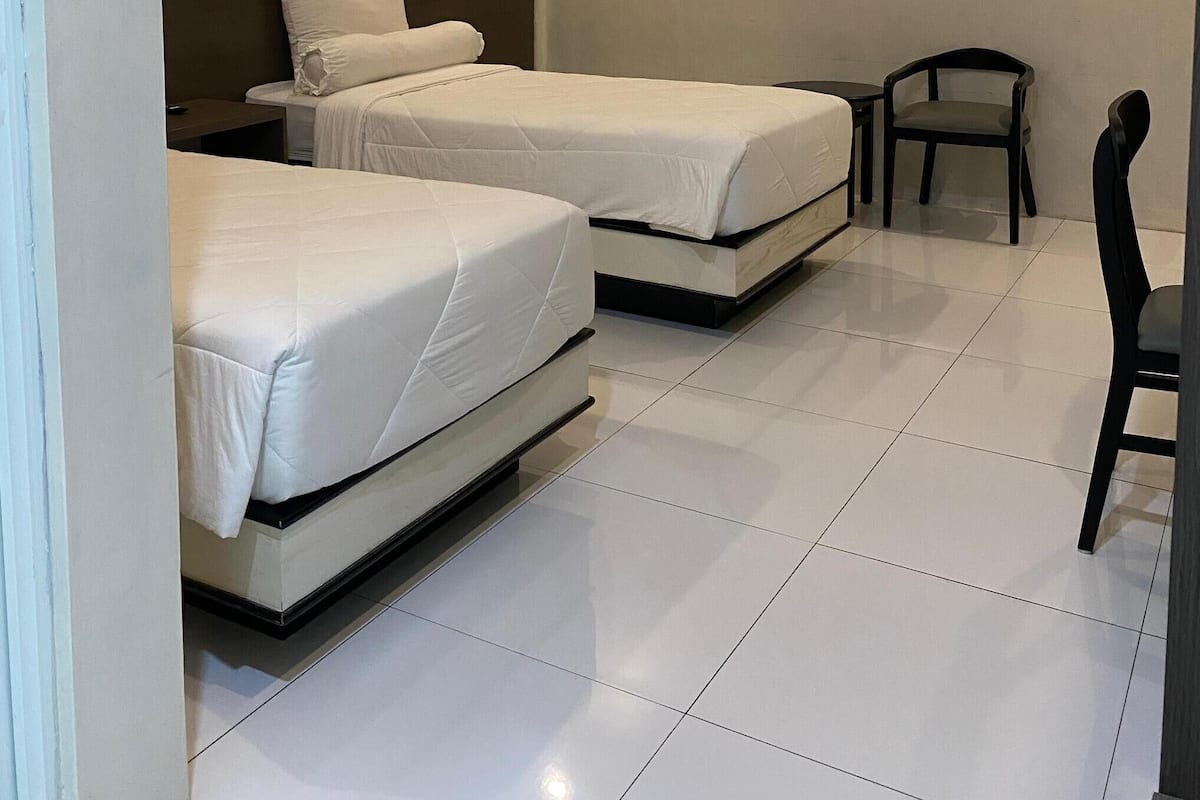 Una habitación con dos camas, una silla y una mesita.