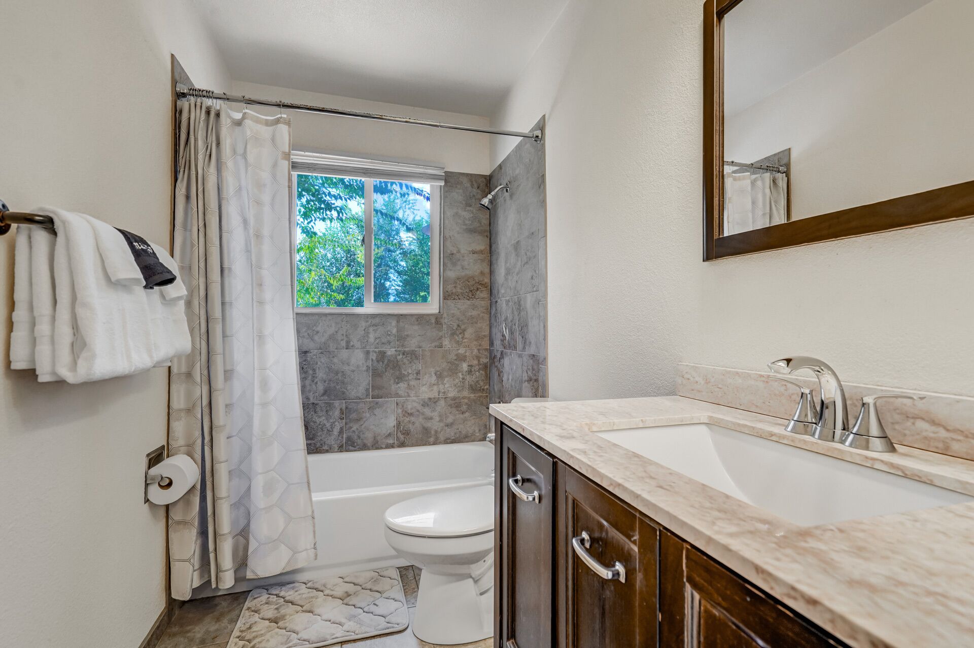 Un baño con bañera, inodoro y lavabo con espejo.
