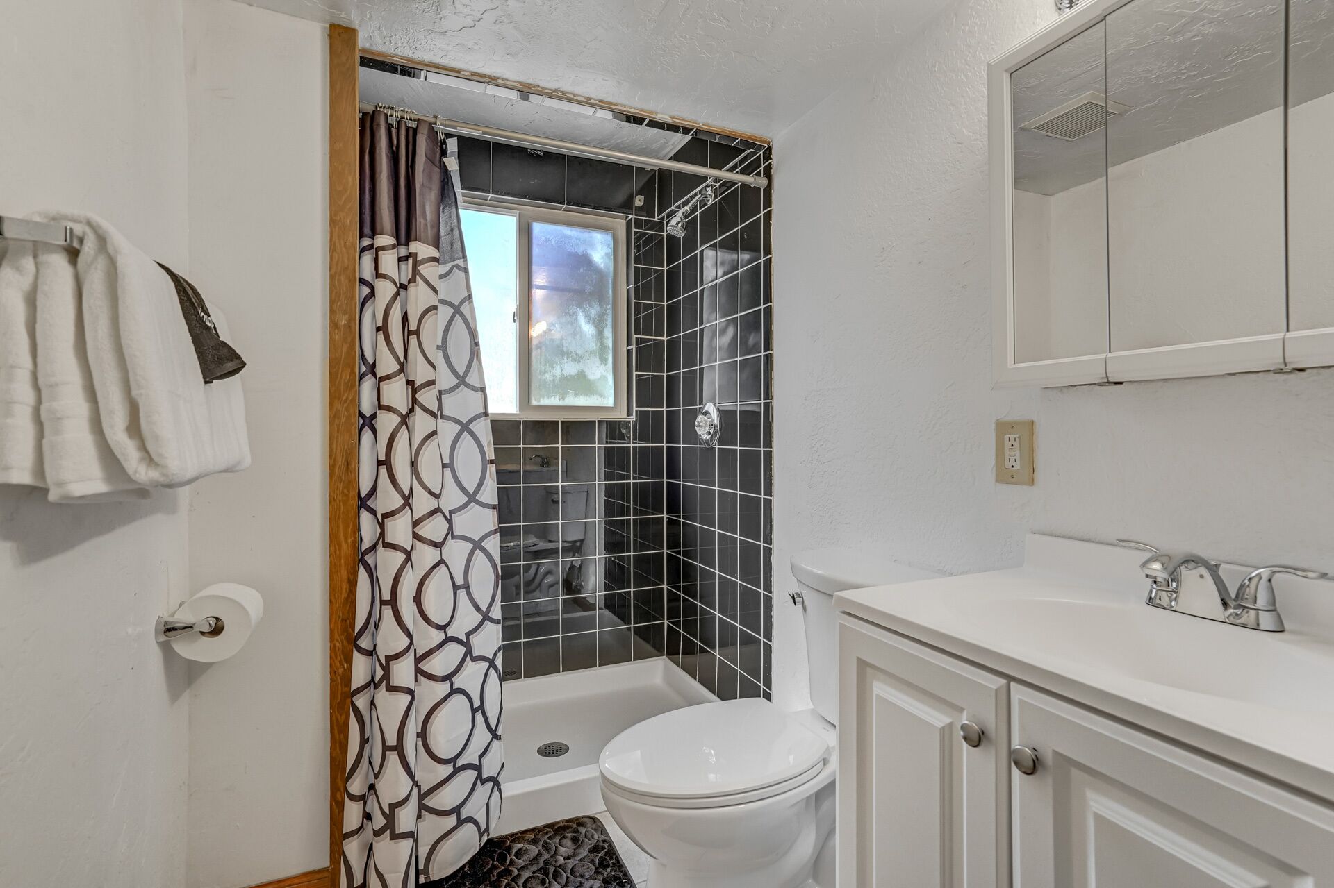 A bathroom with a shower, toilet, and sink.