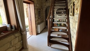 A spacious room with a stone wall, a wooden staircase, and a window with curtains. - Beautiful, Unique, 'stone-built villa on the outskirts of Peyia  (Peyia)