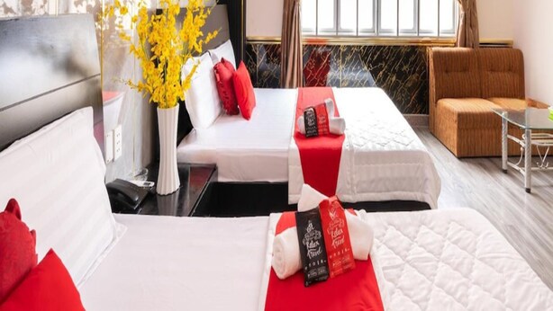 Una habitación de hotel con dos camas, un sofá, una mesita y una ventana con cortinas.