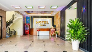 Un vestíbulo de hotel con una máquina expendedora de Coca-Cola, una recepción y una escalera.