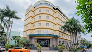 Un hotel de varios pisos con fachada curva, una entrada destacada y un letrero que dice 'HOTEL-TAHAM'.