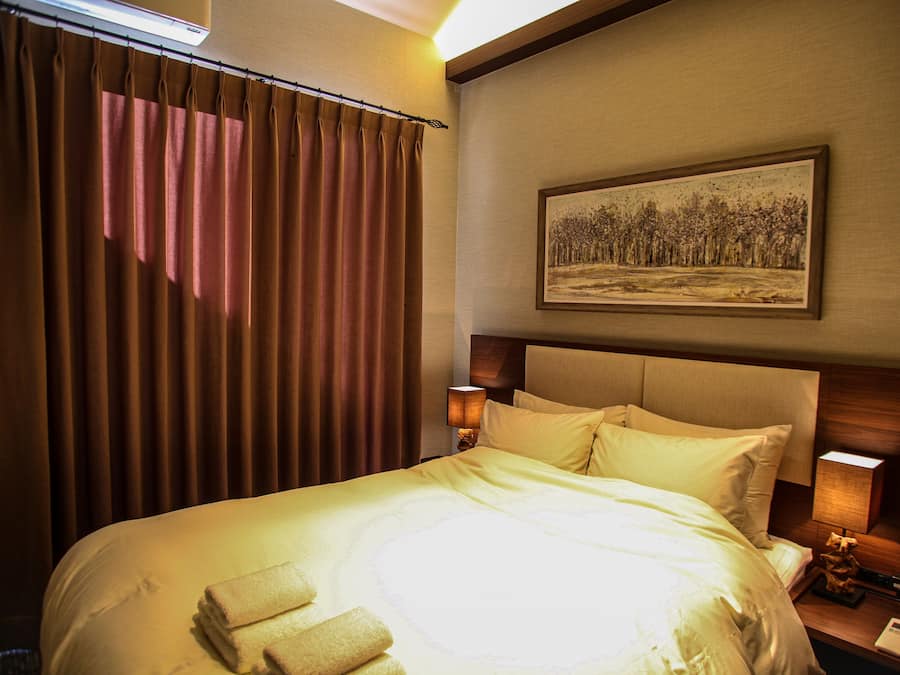 Une chambre d’hôtel avec un grand lit, une tête de lit, une table de chevet avec une lampe et un tableau au mur.