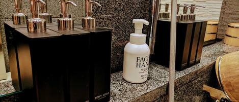 A bathroom with multiple dispensers for shampoo, conditioner, body soap, and face wash.