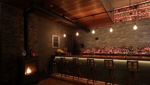 A bar area with a stone wall, a fireplace, and wooden bar stools. - Hotel Kaze no yama (Iida)