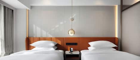 Habitación de hotel con dos camas, una mesita de noche, un teléfono y una lámpara fijada a la pared.