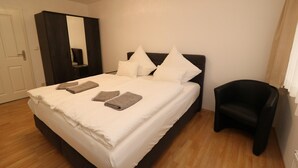 A bedroom with a bed, a wardrobe, a chair, and a mirror. - Apartment in Essen with Balcony (Essen)