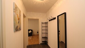 A hallway with a black metal shelf unit, a large mirror, and a painting on the wall. - Apartment in Essen with Balcony (Essen)