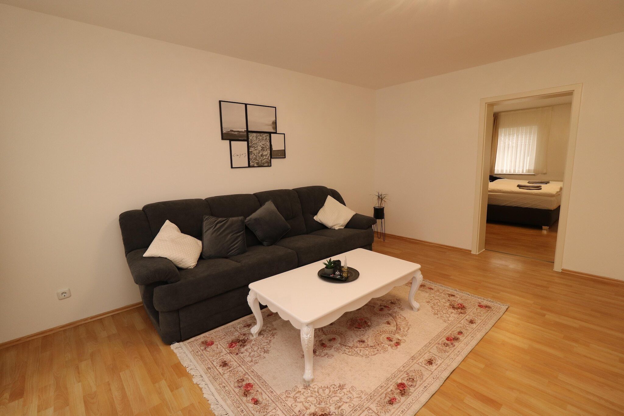A living room with a dark grey sofa, a white coffee table, and a patterned rug.