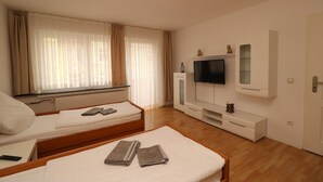 A hotel room with two single beds, a TV on a white cabinet, and a window with sheer curtains. - Apartment in Essen near Messe Essen (Essen)