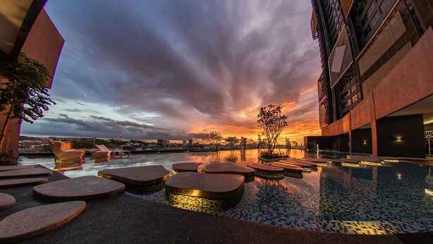 A rooftop pool area with a sunset view, modern architecture, and seating around the pool. - Arte Cheras (Kuala Lumpur)