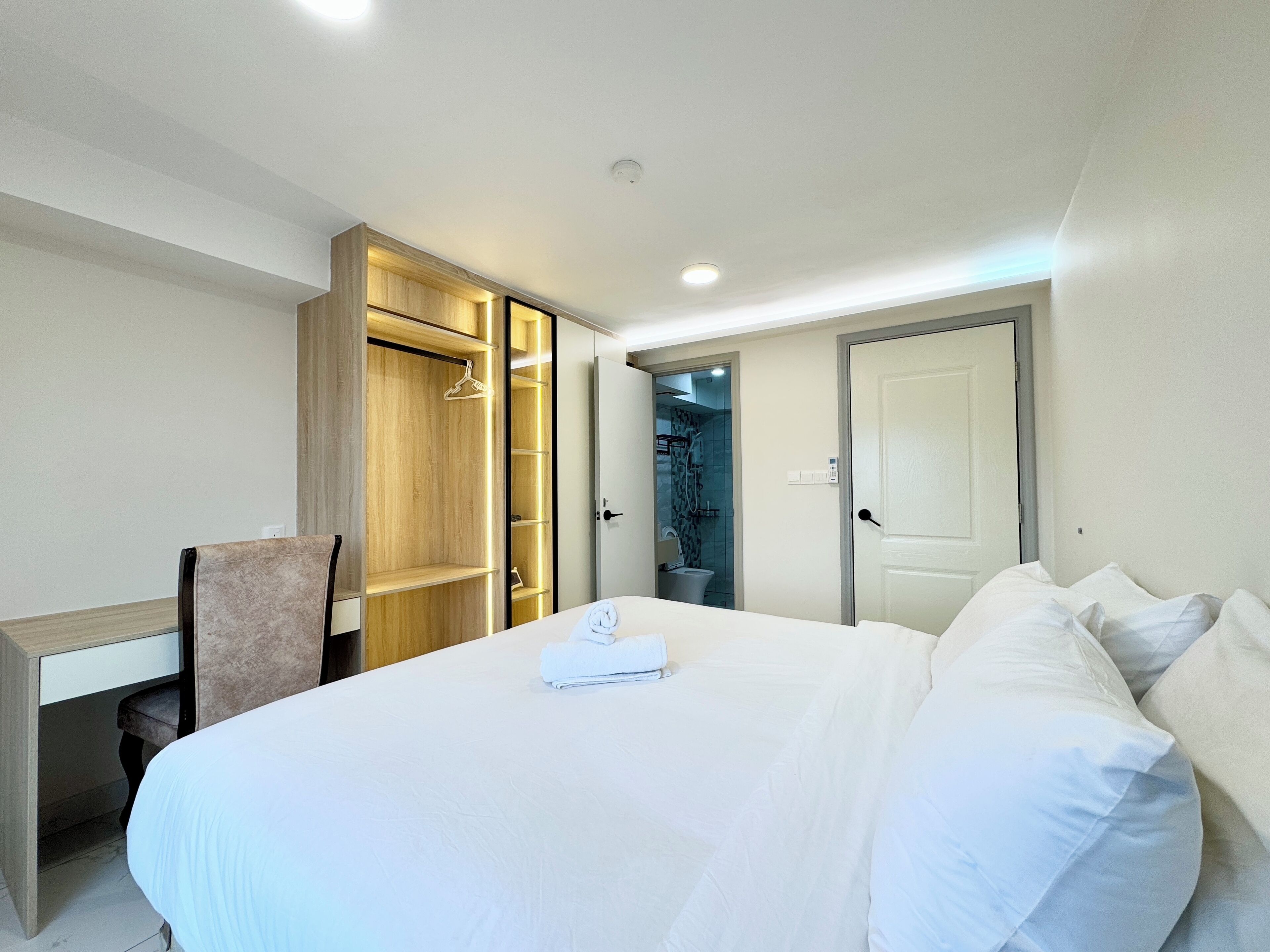 Een hotelkamer met een groot bed, een bureau, een kledingkast en een badkamer die door een open deur zichtbaar is.