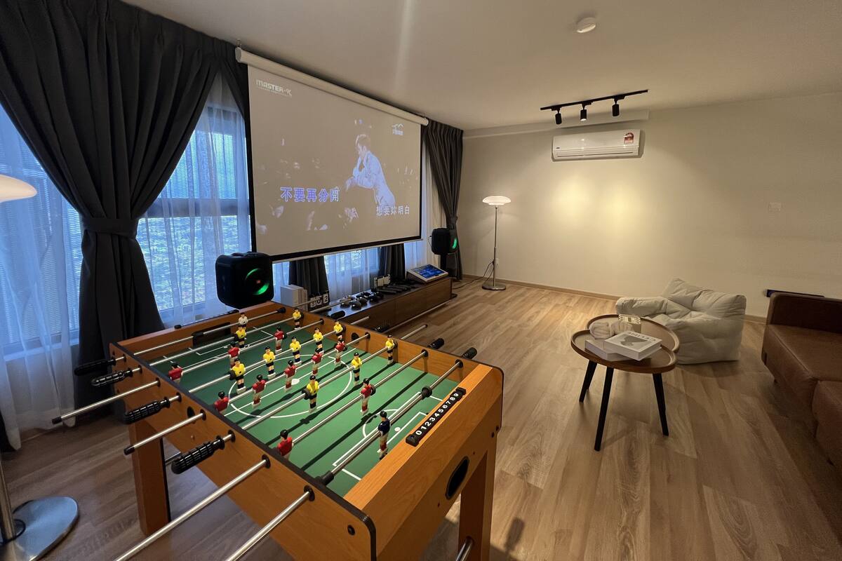 A room with a foosball table, a projector screen, a sofa, and a coffee table.