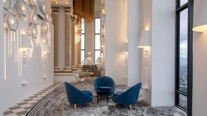 A modern interior with a checkered floor, a seating area with blue chairs, and a view through a large window. - Arte Cheras (Kuala Lumpur)