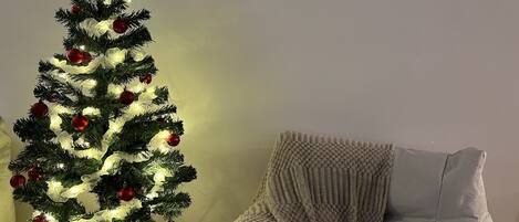 Un sapin de Noël décoré de guirlandes lumineuses et d’ornements, surmonté d’une étoile, et une boîte à cadeaux contenant une carte illustrée.