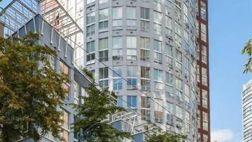 A modern high-rise building with a cylindrical shape, featuring a glass facade and multiple balconies.