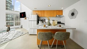 Une cuisine moderne dotée d’un îlot central, de meubles en bois et d’une grande fenêtre qui laisse entrer la lumière naturelle.