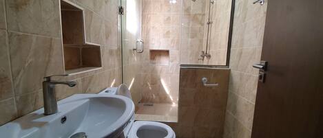 A bathroom with a sink, toilet, and shower.