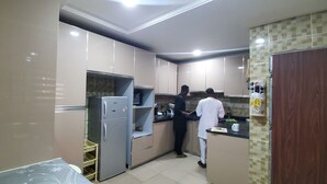 A modern kitchen with stainless steel appliances, a microwave, and a refrigerator. There are cabinets and a countertop with various kitchen items. - Hilton Summer Apartments (Abuja)