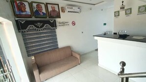 A reception area with a sofa, a reception desk, and wall-mounted clocks. - Hilton Summer Apartments (Abuja)